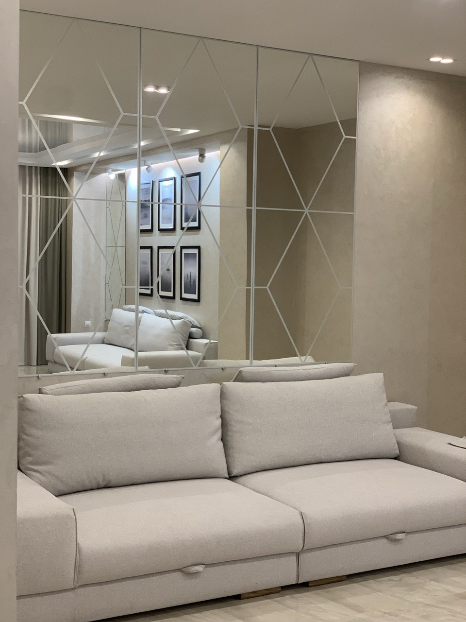Jasna sofa modułowa na tle ściany wyłożonej fazowanymi lustrami — realizacja Bellissimo Home.