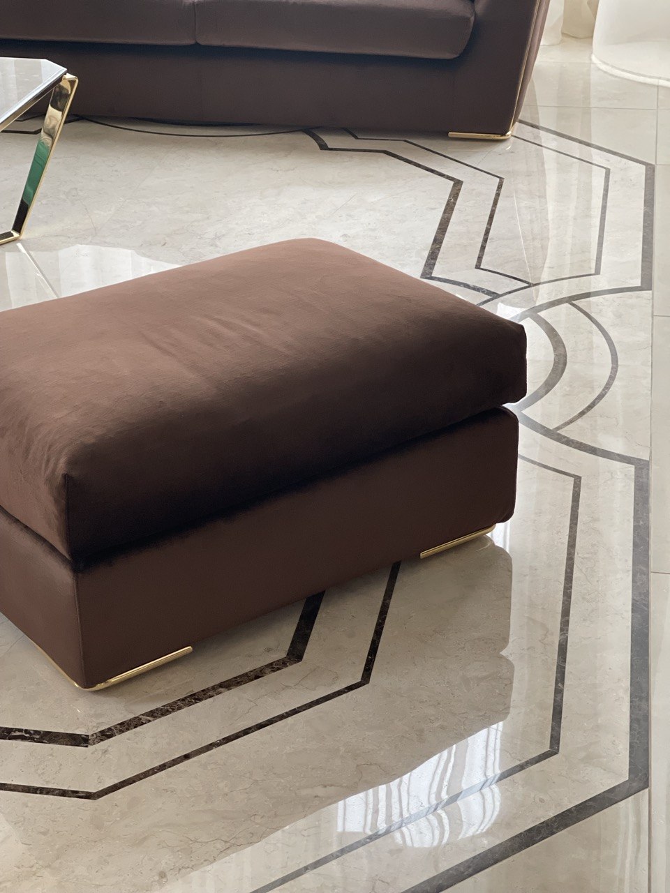 Welurowy puf na złotych nóżkach na marmurowej posadzce z intarsją — detal realizacji Bellissimo Home.