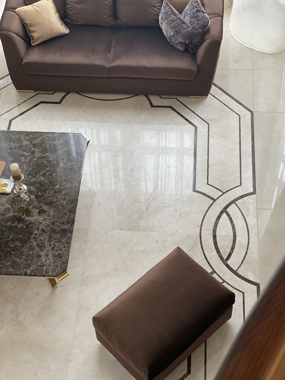 Luksusowa strefa wypoczynkowa z brązową sofą tapicerowaną, pufem oraz stolikiem z ciemnego marmuru. Realizacja projektu w Monako przez Bellissimo Home (showroom: ul. ks. Witolda 34a, 50-202 Wrocław) we współpracy z autorskim studiem @studio_reminterior.